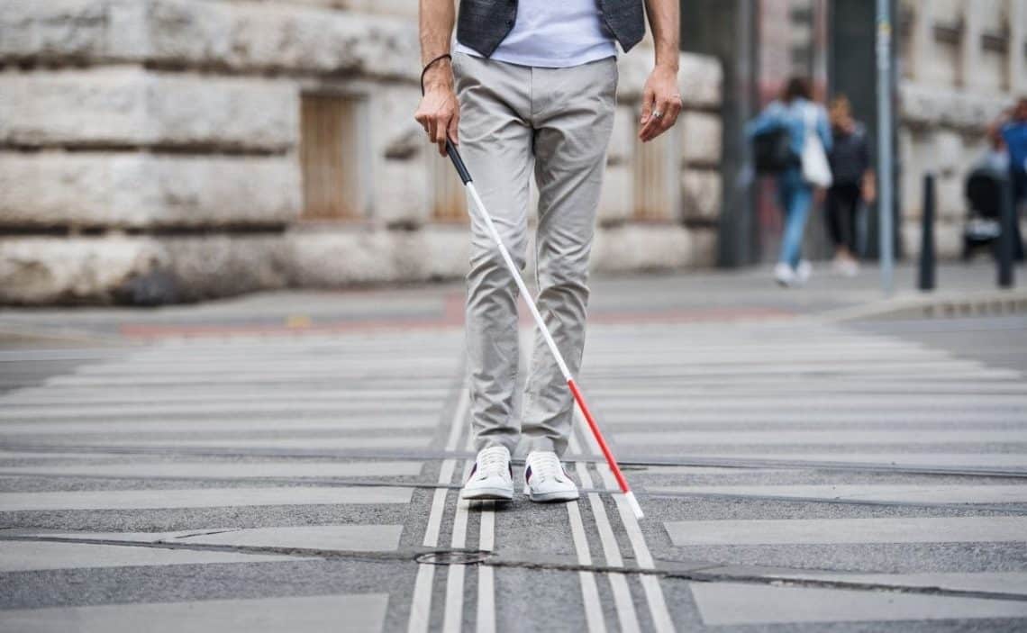 Persona caminando con bastón por vía accesible.