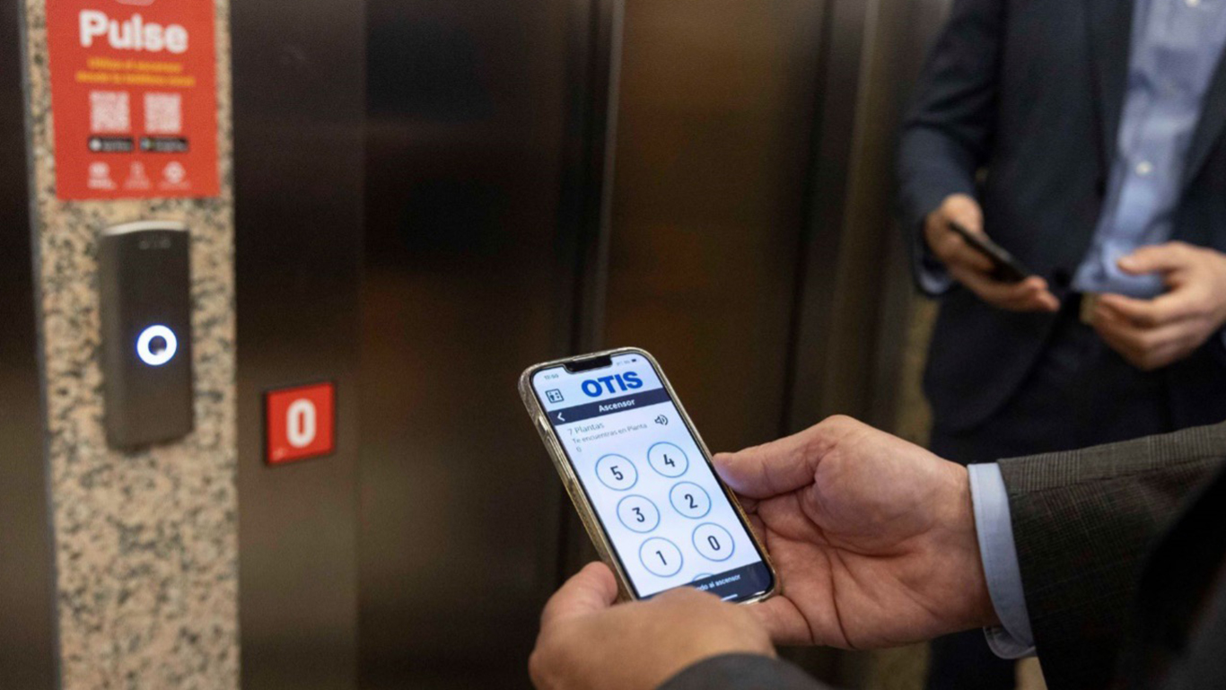usuario frente a un ascensor con aplicación Pulse instalada en su teléfono móvil